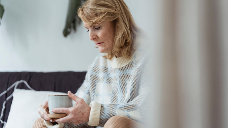 Woman in her fifties sitting quietly on her sofa at home