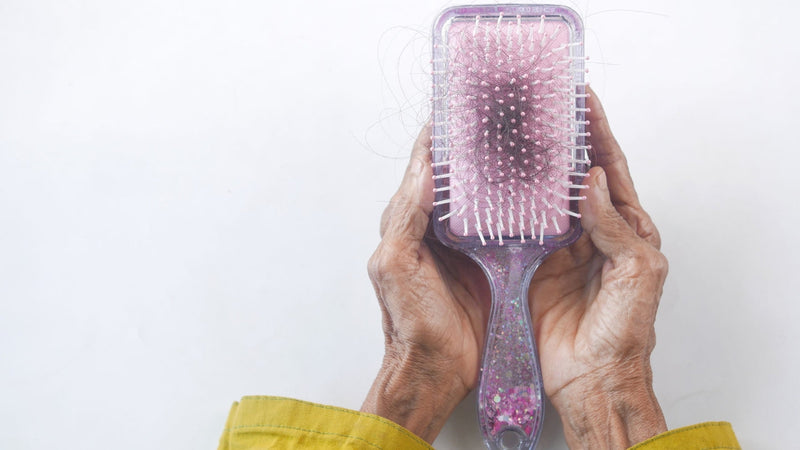 Older hands holding a hairbrush full of shed hair