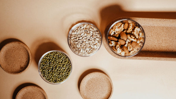 Bowls of seeds and a jar of nuts on a counter