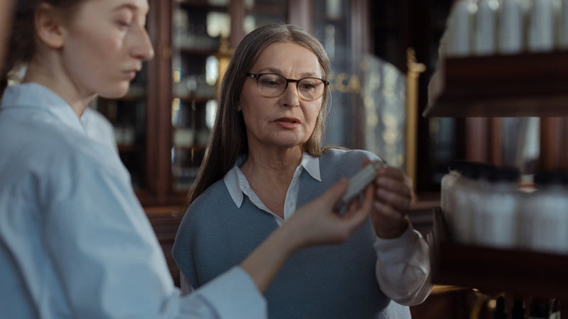Two women comparing products on a pharmacy shelf