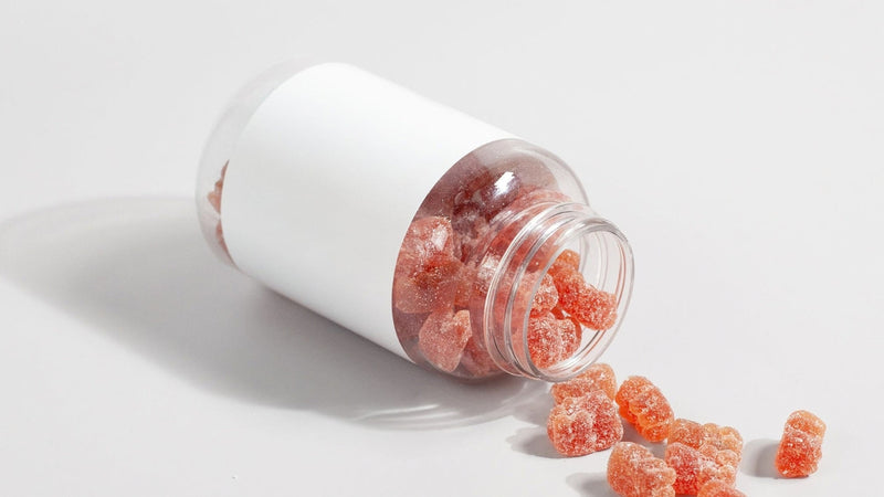 Generic supplement gummies spilling from a plain jar