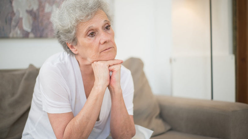 Woman sitting thoughtfully on her sofa