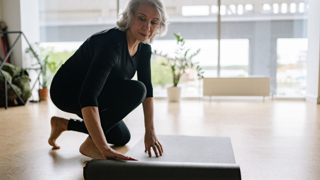 Mature woman rolling out a yoga mat at home
